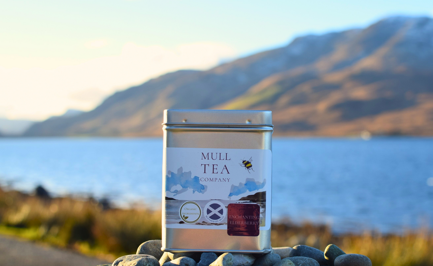 Organic Fruit tea with a Loch and mountains behind it