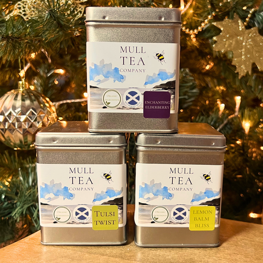 Three organic tea caddies stacked in a triangle in front of a Christmas tree
